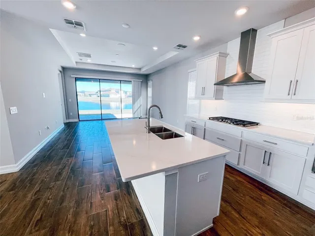 a kitchen with a sink a stove cabinets and wooden floor