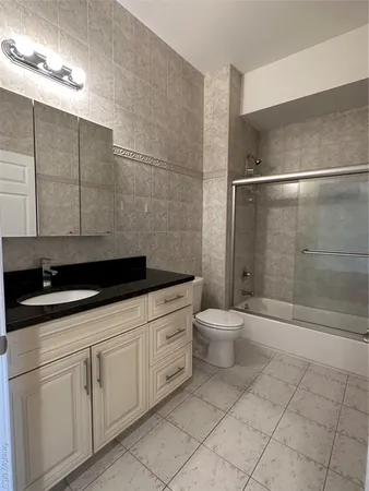 a bathroom with a granite countertop sink a toilet and shower