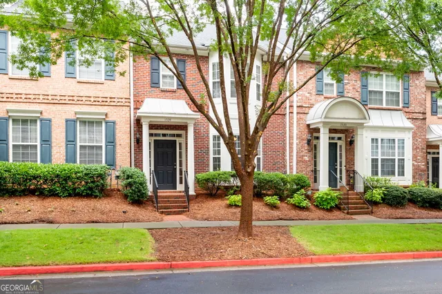 a front view of a house with garden and trees