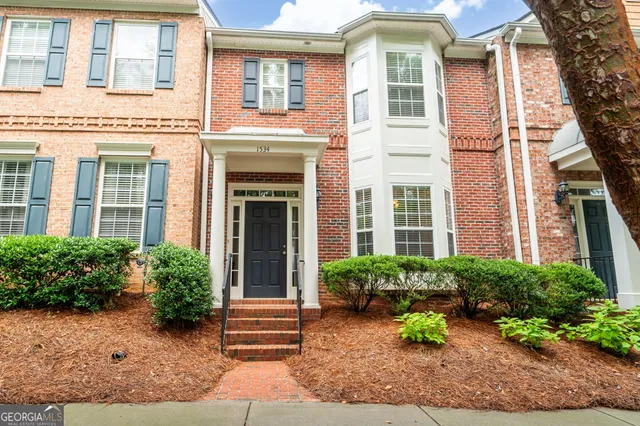 a view of a house with potted plants and a bench