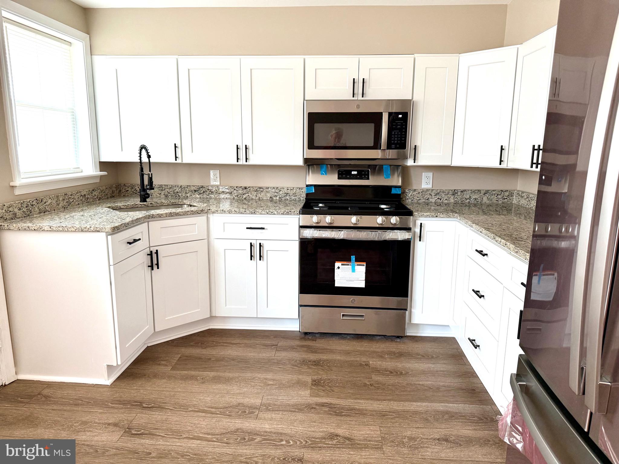 a kitchen with stainless steel appliances granite countertop a stove a sink and a microwave