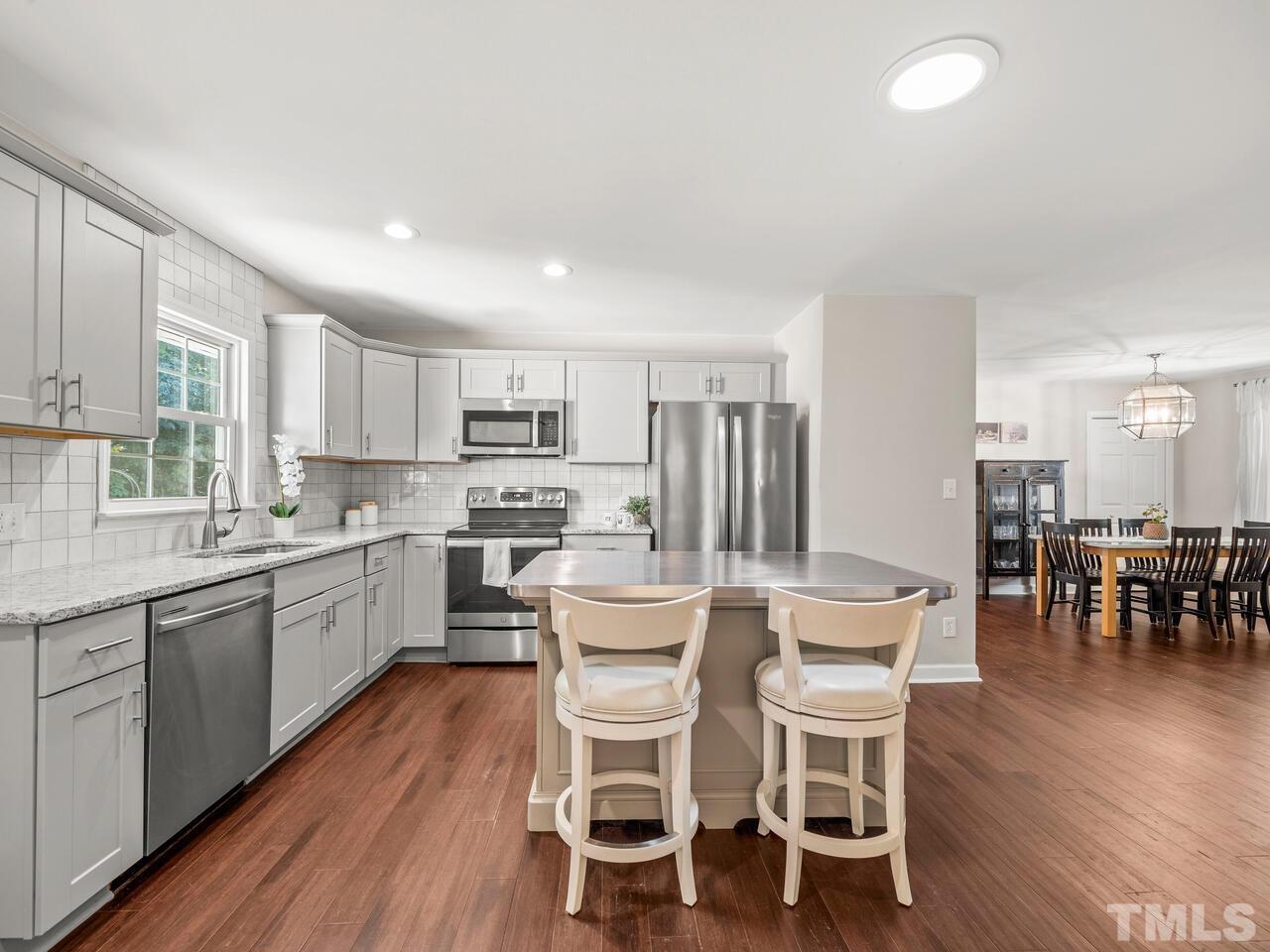430 Obie Drive Durham, NC 27713 - Photo 12 of 35 a kitchen with a dining table chairs wooden floor cabinets and stainless steel appliances