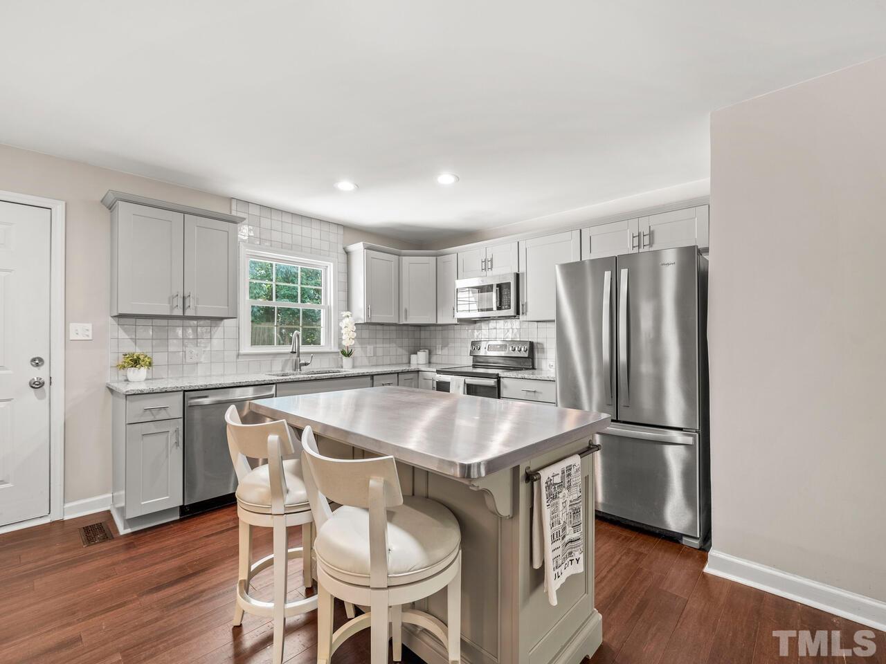 430 Obie Drive Durham, NC 27713 - Photo 10 of 35 a kitchen with stainless steel appliances granite countertop a sink a stove a refrigerator and white cabinets with wooden floor