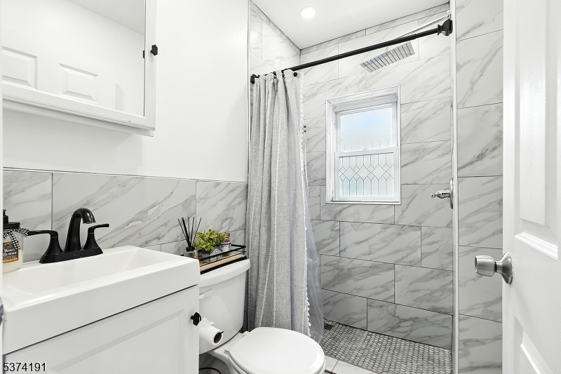 50 Oak Street Paterson, NJ 07501 - Photo 13 of 28 a bathroom with a sink a toilet and shower
