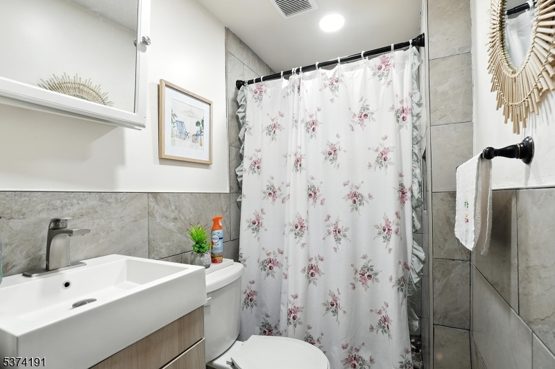 50 Oak Street Paterson, NJ 07501 - Photo 10 of 28 a bathroom with a sink a toilet and shower curtain