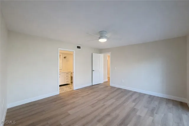 a view of an empty room with wooden floor and closet