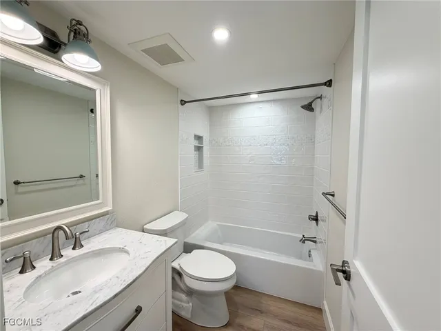 a bathroom with a bathtub shower sink vanity mirror and toilet
