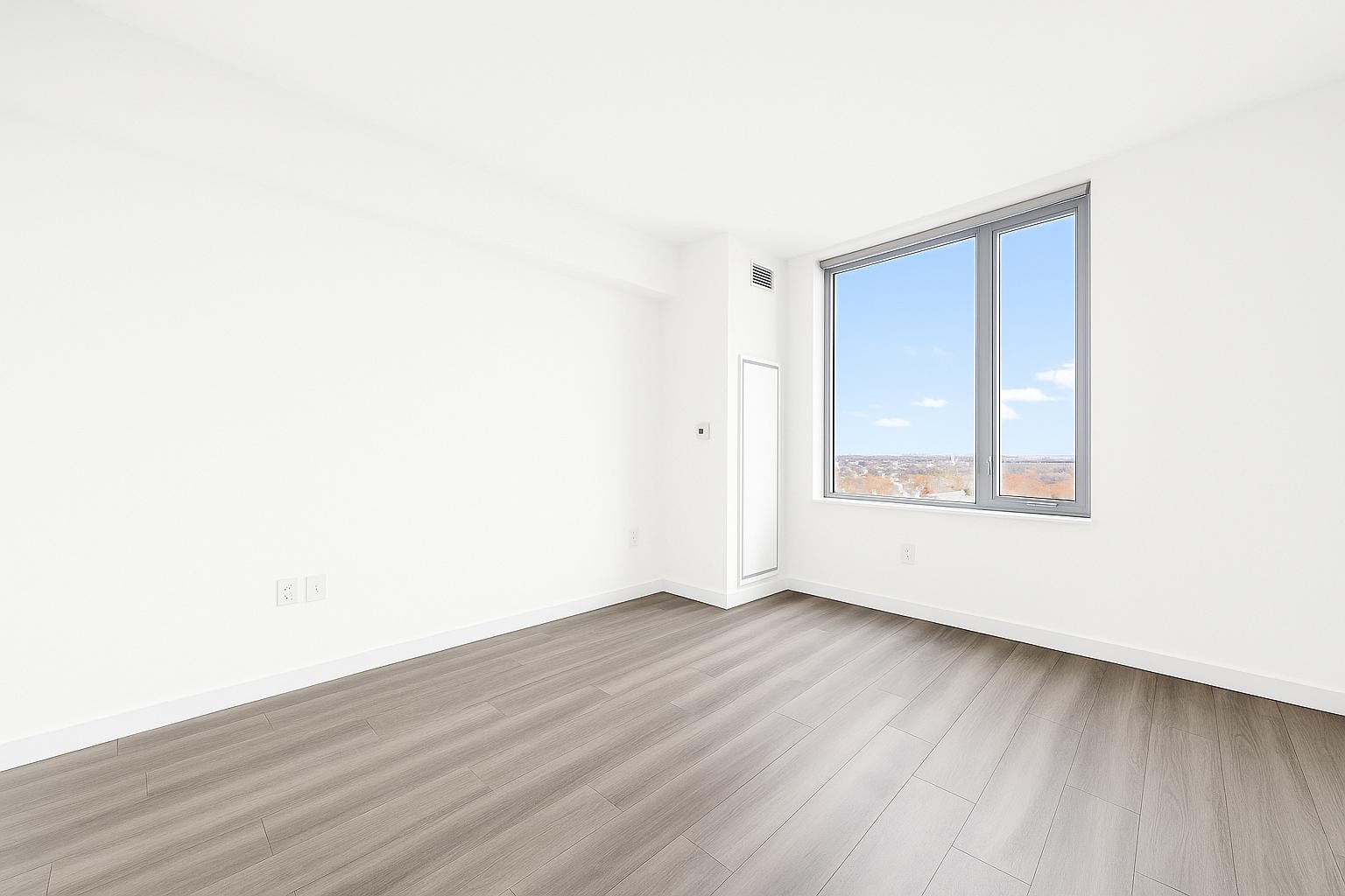 1524 Sheepshead Bay Road, Unit 7G Brooklyn, NY 11235 - Photo 4 of 28 a view of an empty room with wooden floor and a window