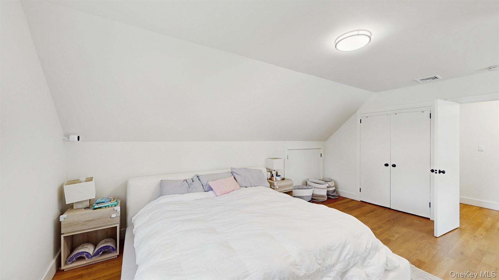 170 Wetherill Road Garden City, NY 11530 - Photo 18 of 23 Bedroom with visible vents, baseboards, a closet, light wood-style floors, and vaulted ceiling
