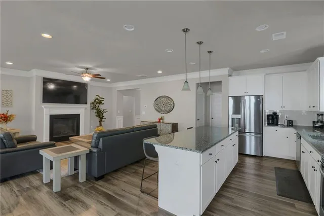 a large living room with stainless steel appliances granite countertop couches a fireplace a flat screen tv and a fireplace