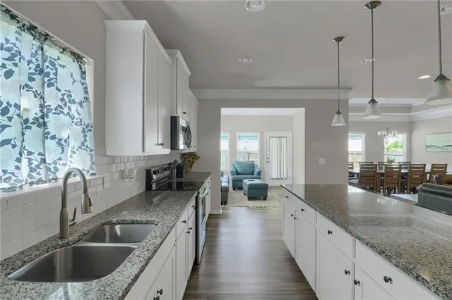 a large kitchen with granite countertop a large counter top space a sink stainless steel appliances and cabinets