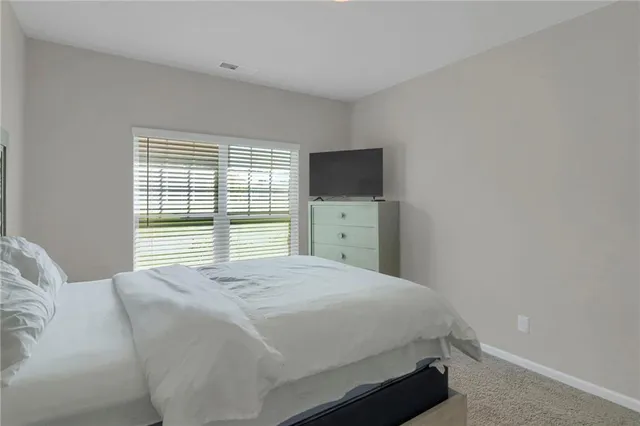 a bedroom with a bed and a flat tv screen on the dresser
