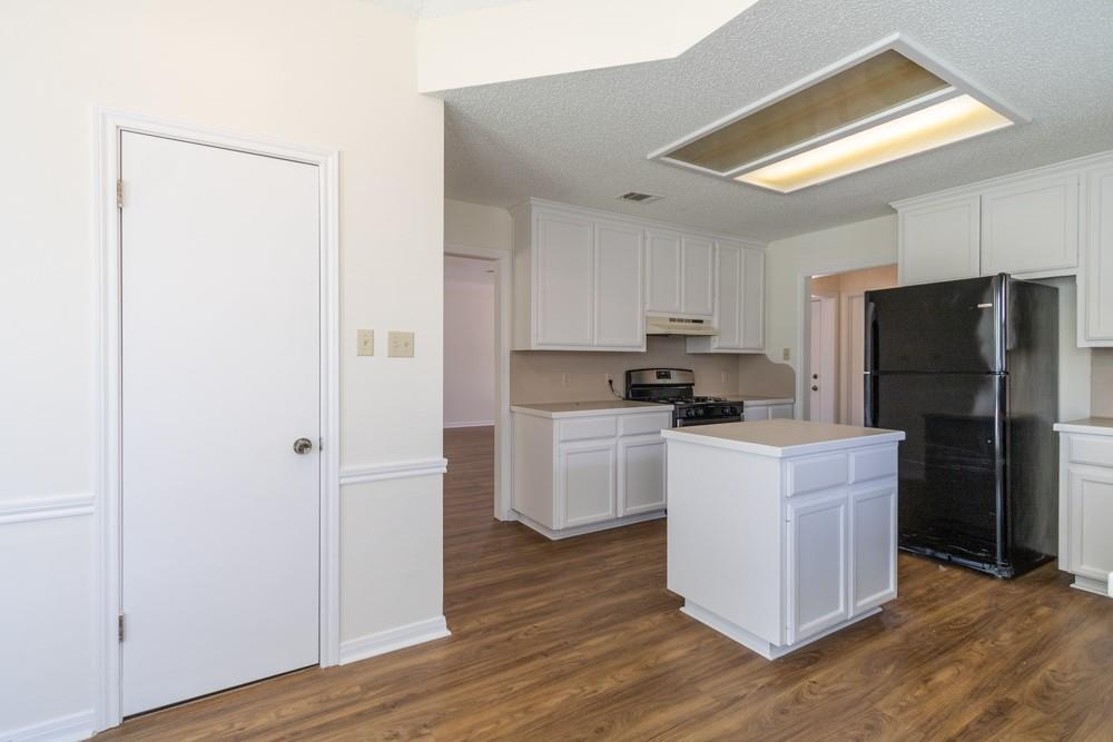 2411 Raintree Path Round Rock, TX 78664 - Photo 11 of 28 a kitchen with a refrigerator a stove top oven a sink and dishwasher with wooden floor