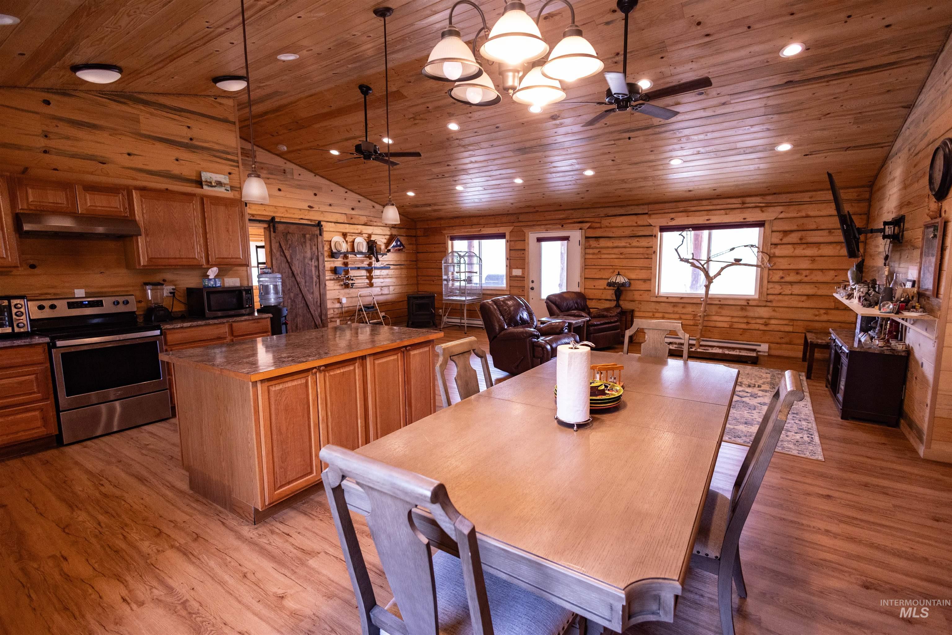 830 Leitch Creek Road Kooskia, ID 83539 - Photo 13 of 49 Dining space with wood ceiling, light wood-type flooring, wood walls, a ceiling fan, and a barn door