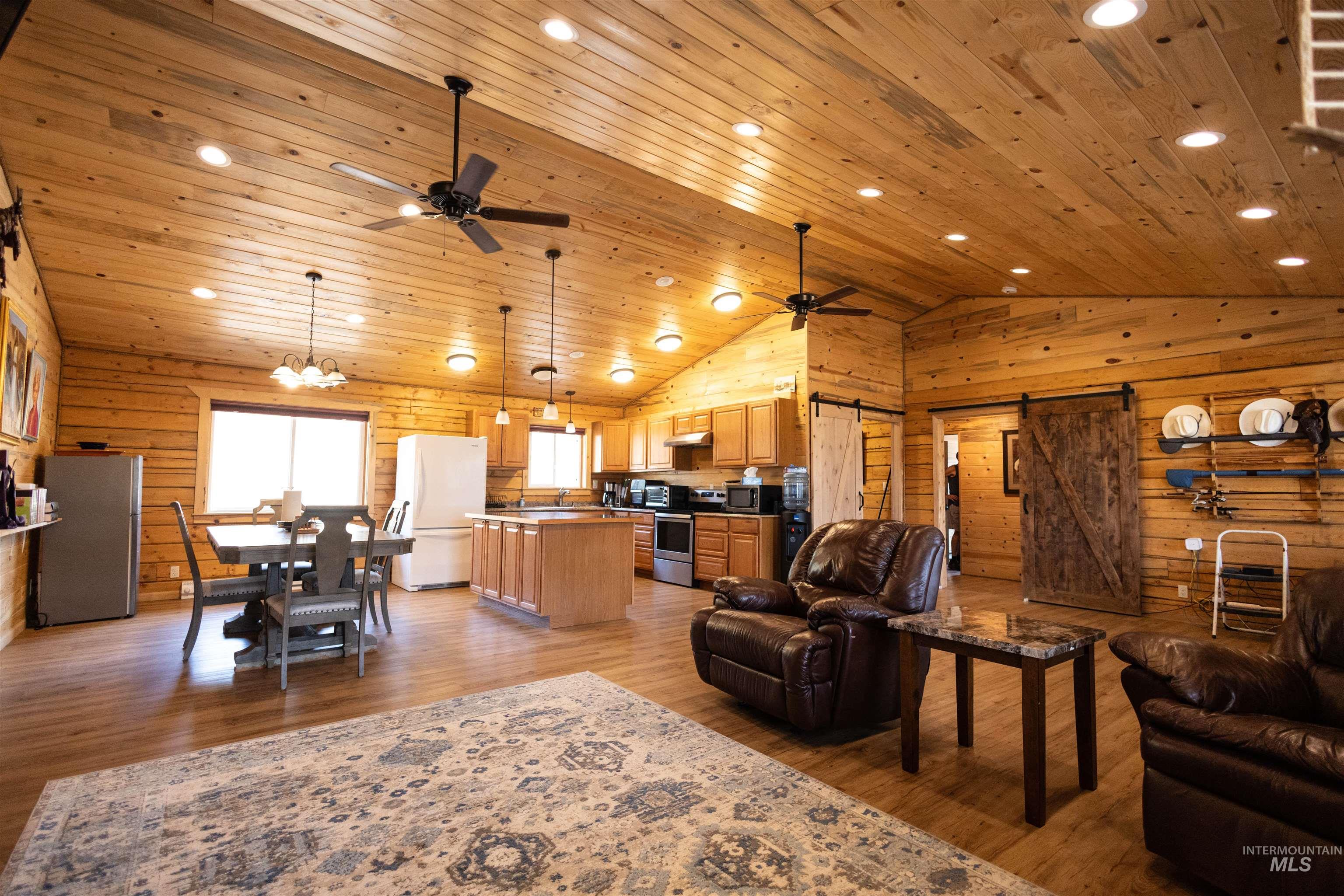 830 Leitch Creek Road Kooskia, ID 83539 - Photo 15 of 49 Living area with a barn door, light wood-type flooring, wooden ceiling, ceiling fan, and wooden walls