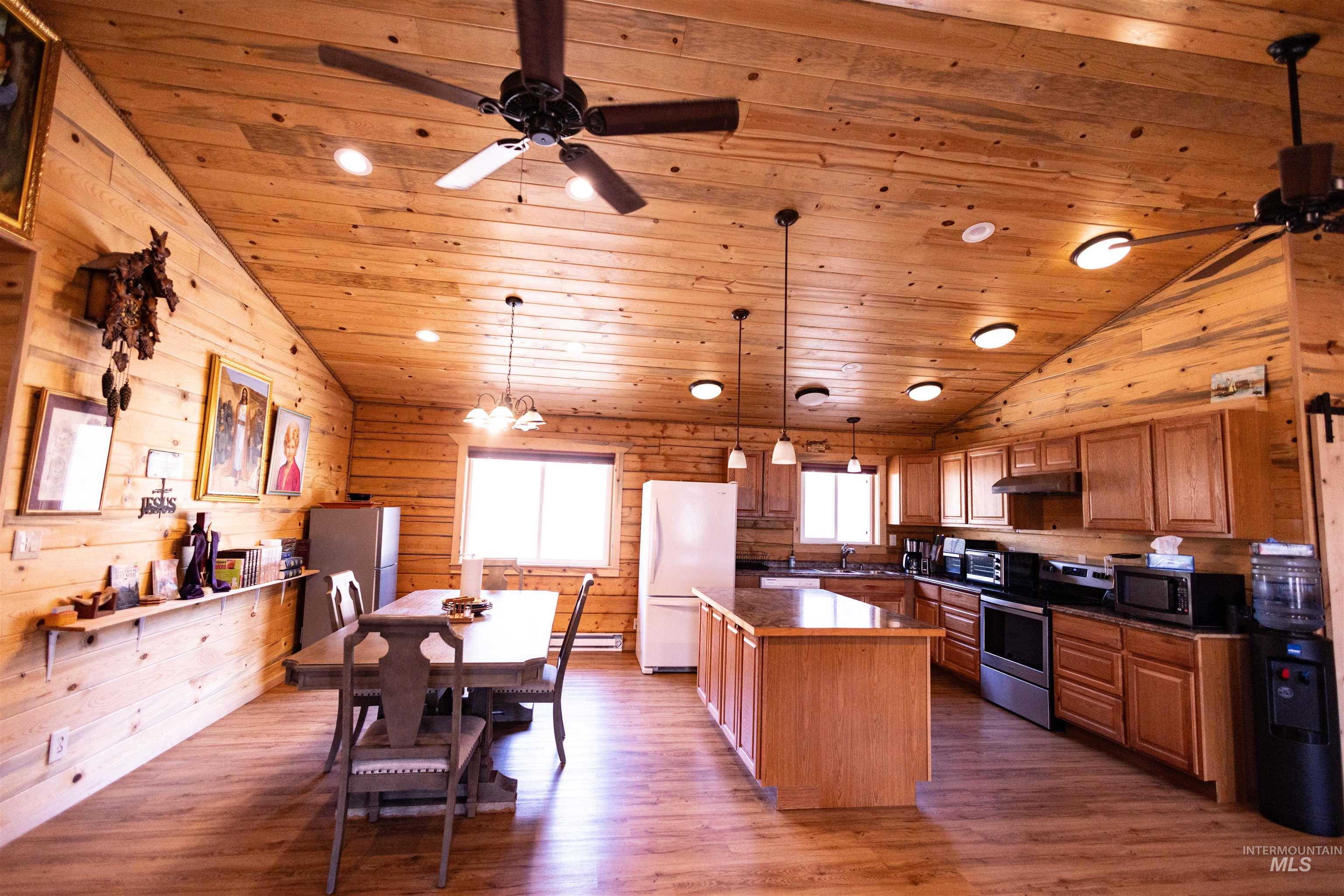 830 Leitch Creek Road Kooskia, ID 83539 - Photo 16 of 49 Kitchen with dark countertops, decorative light fixtures, appliances with stainless steel finishes, brown cabinets, and dark wood finished floors