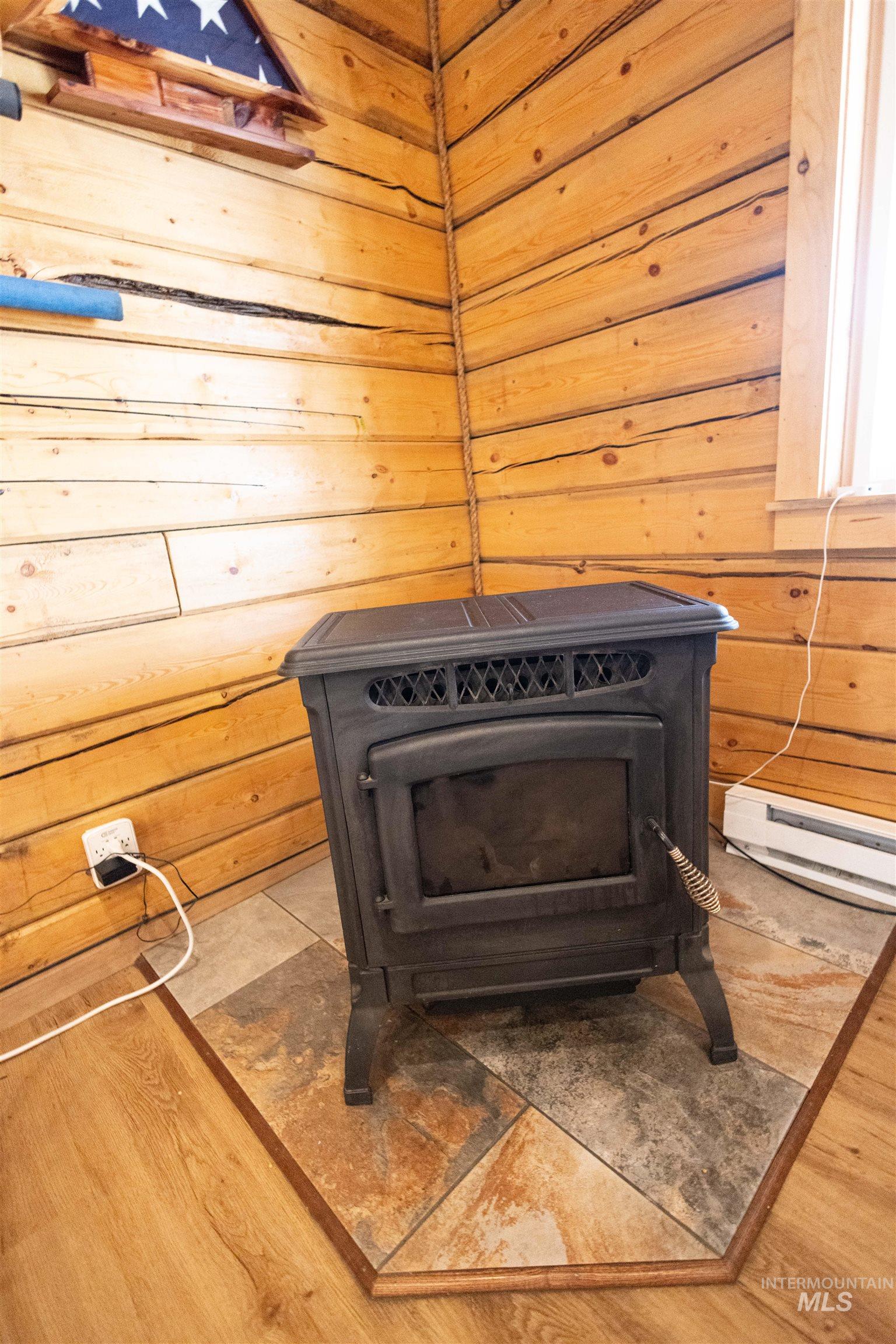 830 Leitch Creek Road Kooskia, ID 83539 - Photo 17 of 49 Detailed view of wooden walls, a wood stove, a baseboard radiator, and wood finished floors