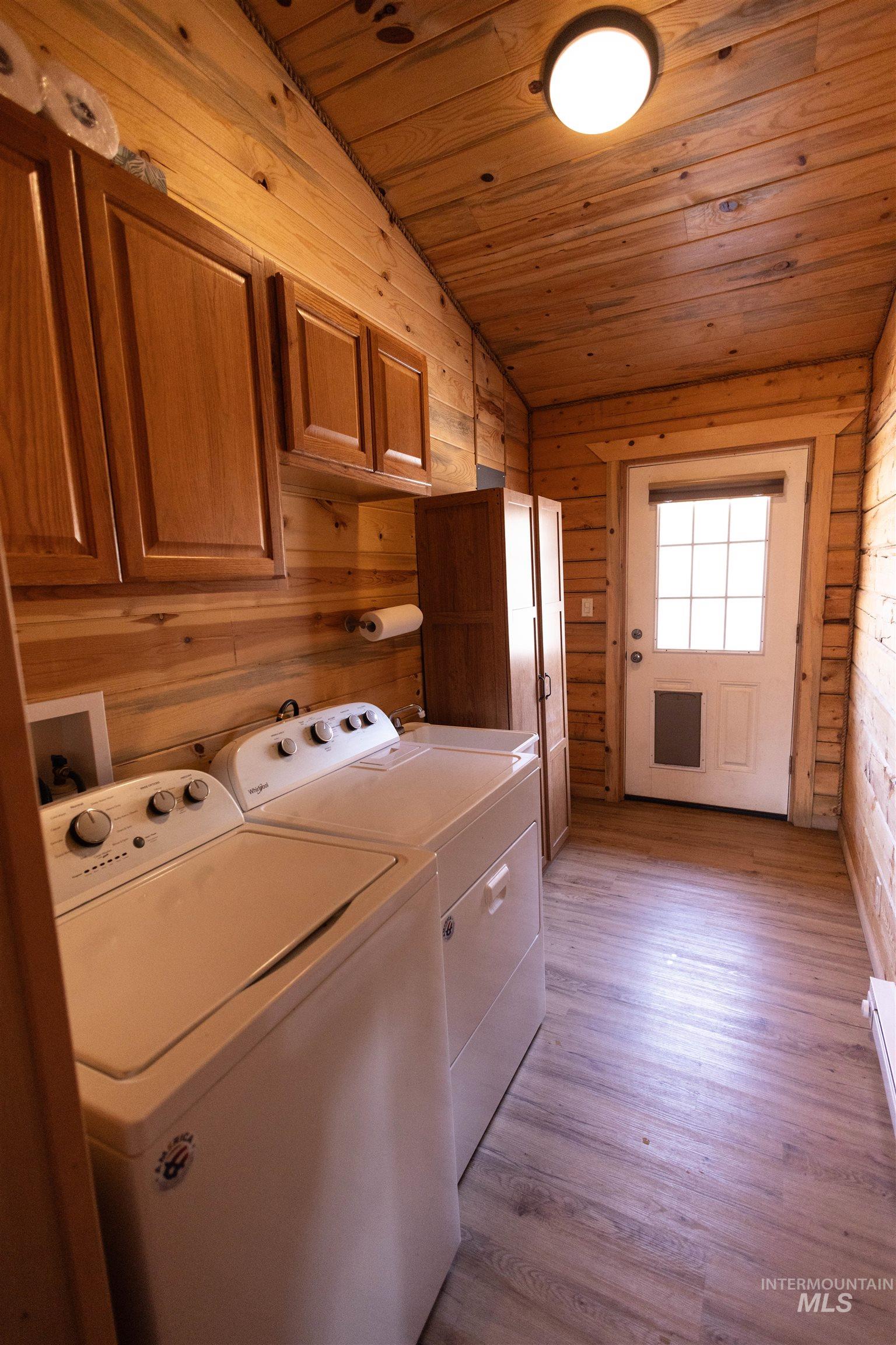 830 Leitch Creek Road Kooskia, ID 83539 - Photo 19 of 49 Laundry room featuring wood walls, light wood finished floors, wood ceiling, cabinet space, and washer and clothes dryer