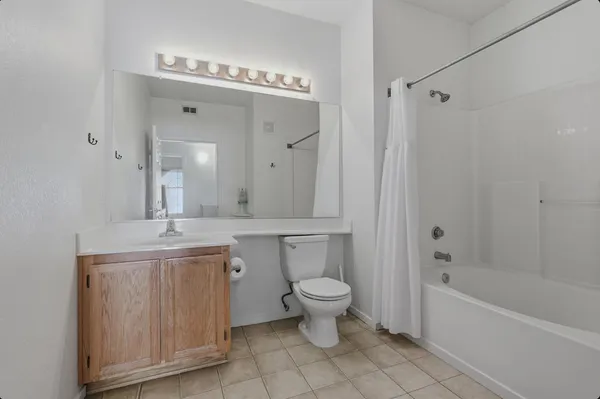a bathroom with a granite countertop sink a toilet mirror and bathtub