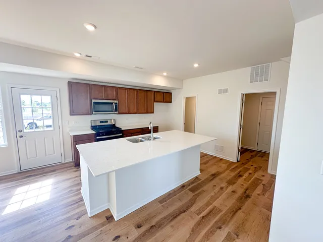 a large white kitchen with wooden floor and a sink