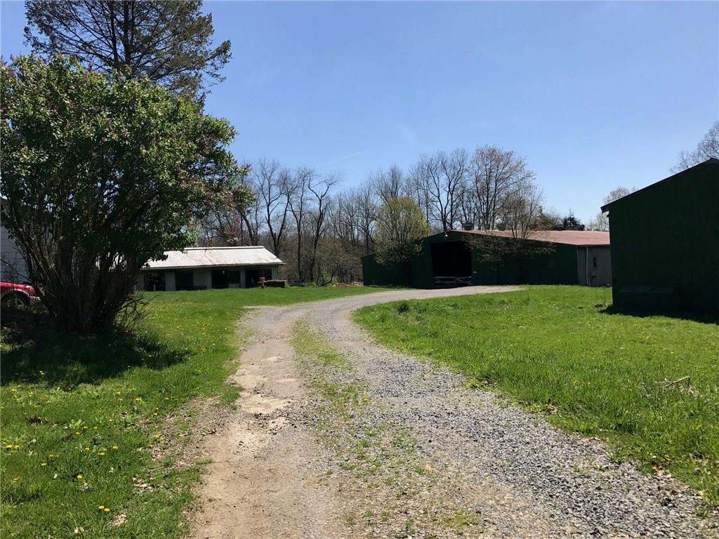 3600 Centerview Road Gibsonia, PA 15044 - Photo 11 of 25 Coming in the driveway, the Log Home is on the far left. Ahead are 3 main buildings on the property. The white "stall barn" with individual stalls and half doors for boarding multiple horses. The mammoth center barn has stalls running both sides with a center area used as an indoor training arena. A tack room, plumbing, and storage is also inside. On the right side is a large "Hay Barn" with obvious and numerous uses.