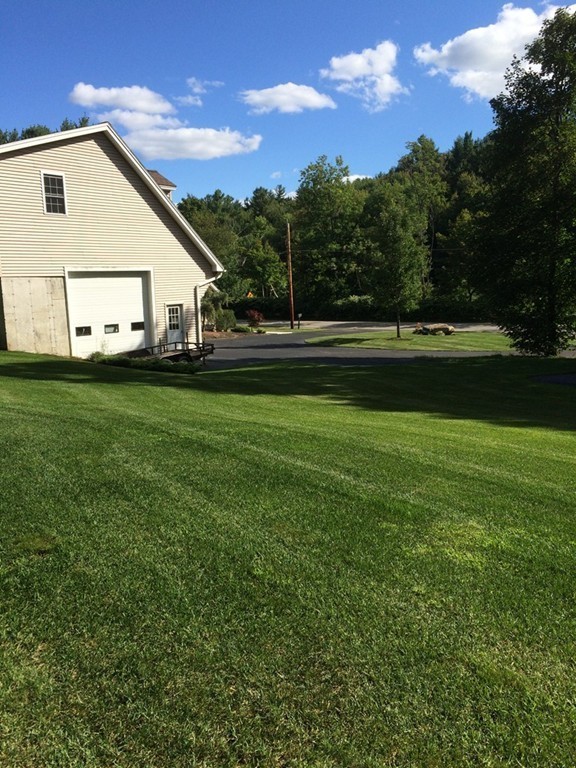 159 Fitchburg Road Ashburnham, MA 01430 - Photo 5 of 13 a view of a white house in front of a big yard with plants and large trees