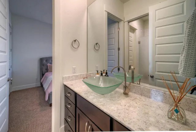 a bathroom with a granite countertop sink a mirror and shower