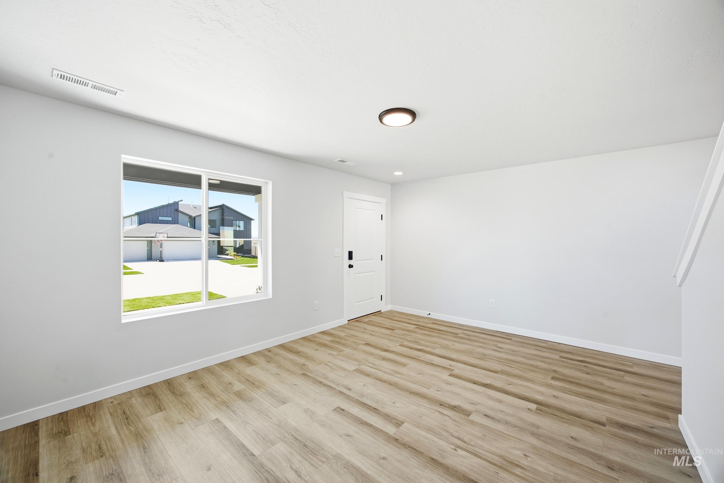 12841 Decatur Street Nampa, ID 83651 - Photo 11 of 30 Spacious room featuring wood-finish flooring, white trim, and a large window