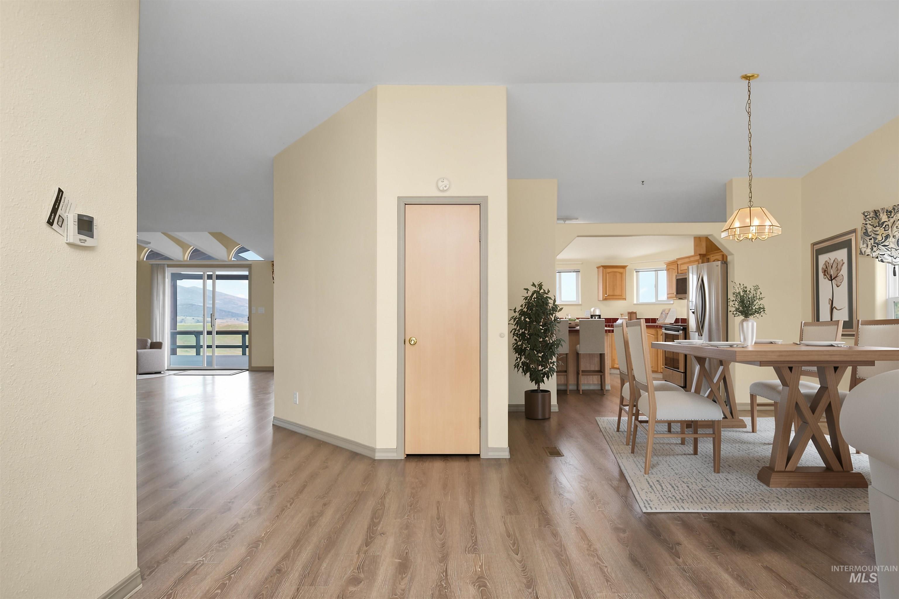 11375 Timber Butte Road Sweet, ID 83670 - Photo 7 of 49 Spacious living area featuring wood-finish flooring, a dining area with a brass chandelier, and a kitchen with an arched entry