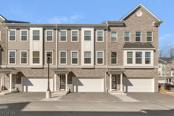 a front view of a building with lot of cars and trees