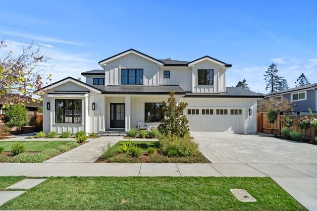 a front view of a house with a yard and potted plants