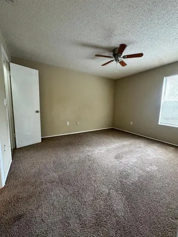 an empty room with a ceiling fan and a window