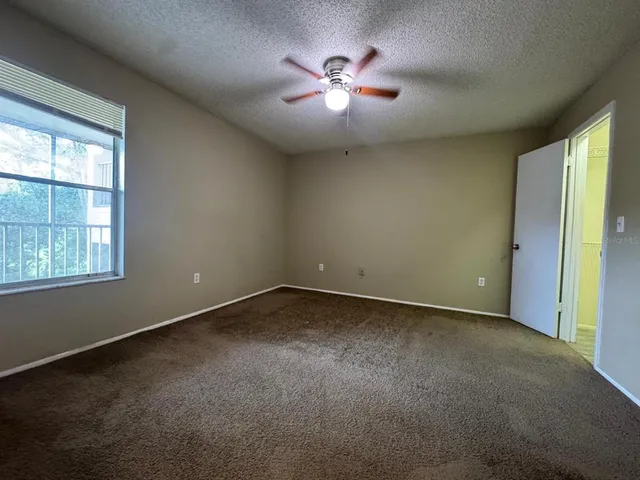 an empty room with windows and fan