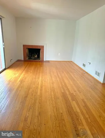 a view of empty room with wooden floor and fireplace