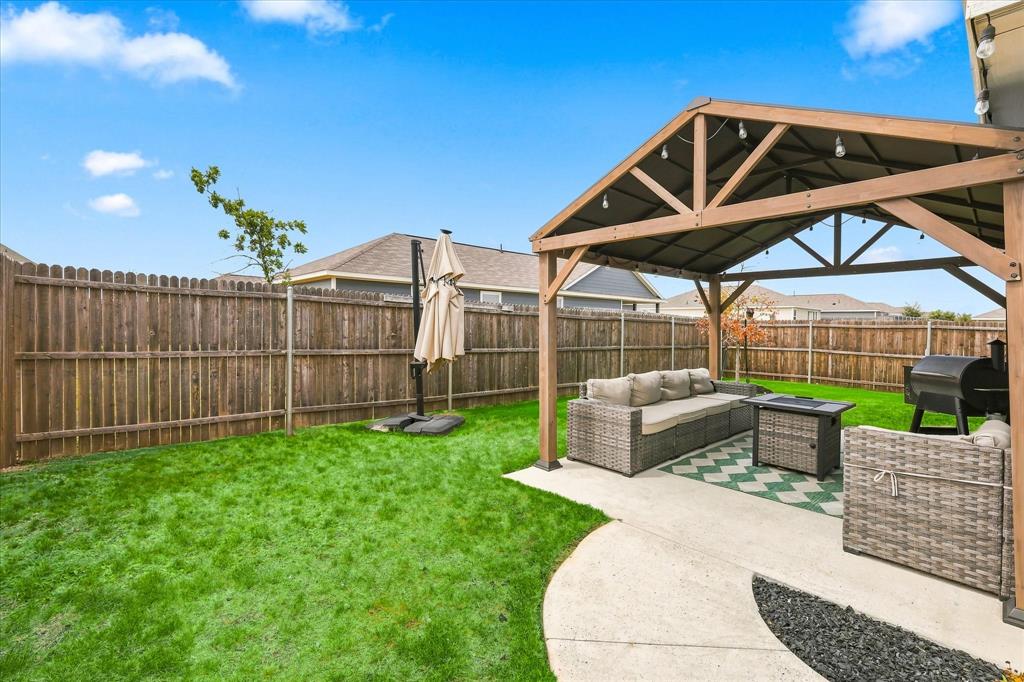 11741 Marcellus Way Rhome, TX 76078 - Photo 29 of 34 Expansive backyard featuring a wood privacy fence, a covered patio structure, and a concrete patio