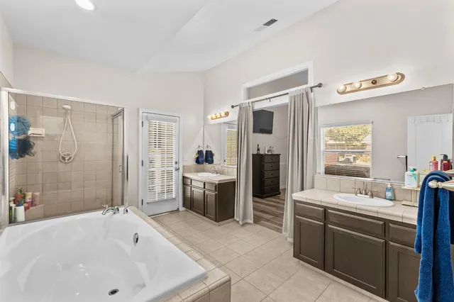 a bathroom with a tub sink a mirror and a shower
