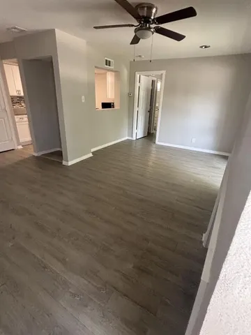 an empty room with wooden floor fan and windows