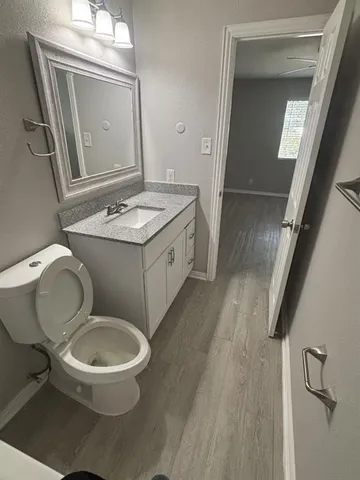 a bathroom with a granite countertop toilet a sink and a mirror