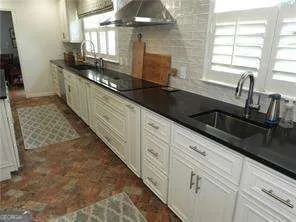 a kitchen with granite countertop a sink a stove and cabinets