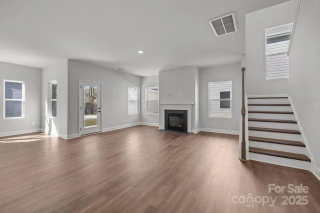 an empty room with wooden floor fireplace and windows