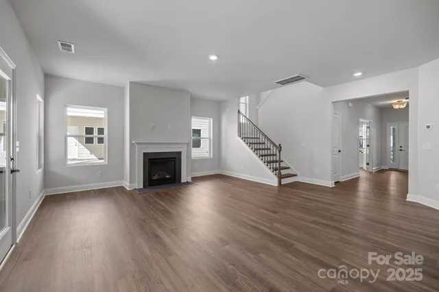 an empty room with wooden floor fireplace and windows