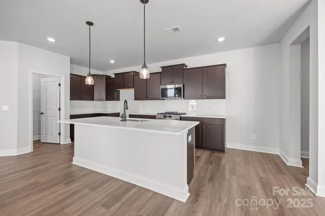 a large kitchen with stainless steel appliances kitchen island a large counter space a sink and a wooden floor