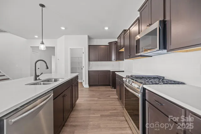 a kitchen with stainless steel appliances granite countertop a sink a stove and a refrigerator