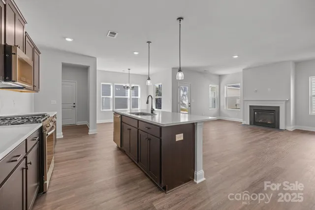 a large kitchen with stainless steel appliances granite countertop a large counter top a stove and a wooden floors