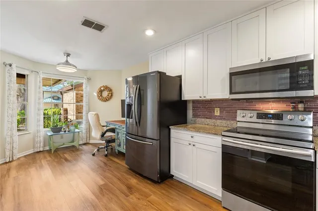 a kitchen with a refrigerator stove and wooden floor
