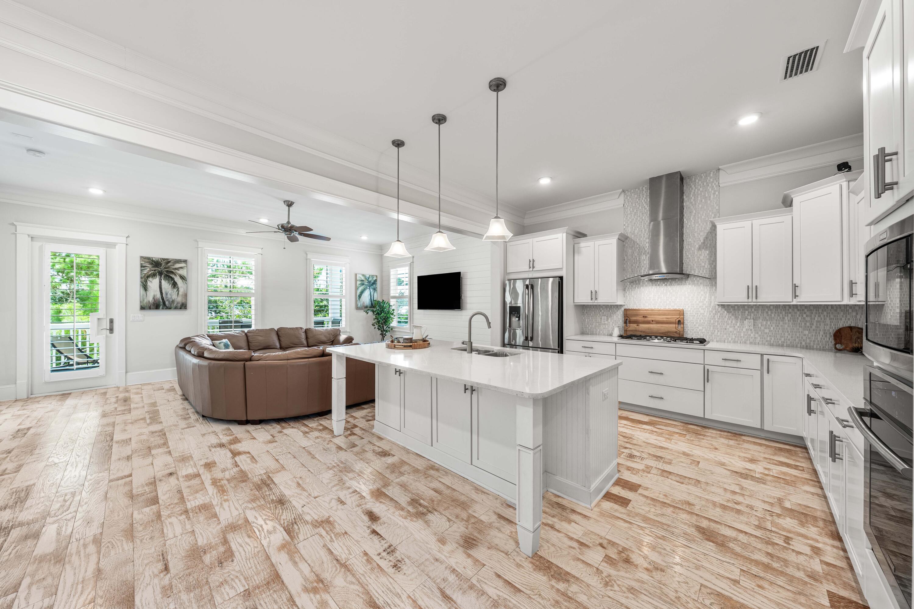 164 Clipper Street Inlet Beach, FL 32461 - Photo 9 of 75 a large kitchen with stainless steel appliances kitchen island granite countertop a stove a sink a refrigerator and white cabinets with wooden floor