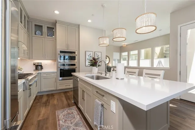 a large white kitchen with kitchen island a large counter space a sink appliances and cabinets
