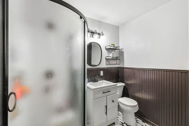 a bathroom with a toilet sink vanity and mirror