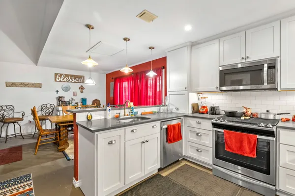 a kitchen with granite countertop a stove sink microwave and cabinets