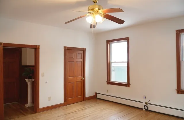 a view of an empty room with window and wooden floor